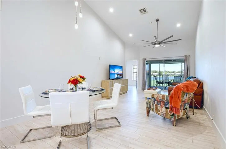 Dining room with high vaulted ceiling, ceiling fan, and light wood-style flooring