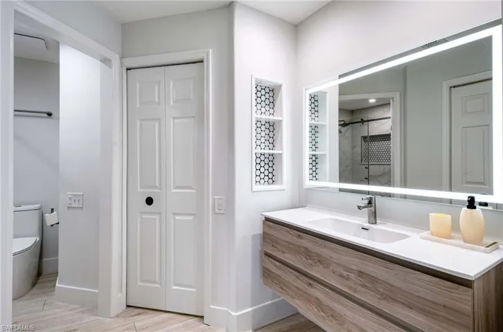 Bathroom with a closet, vanity, tiled shower, and wood tiled floors
