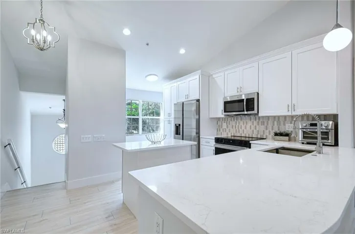 Kitchen featuring decorative light fixtures, a center island, white cabinets, stainless steel appliances, and recessed lighting