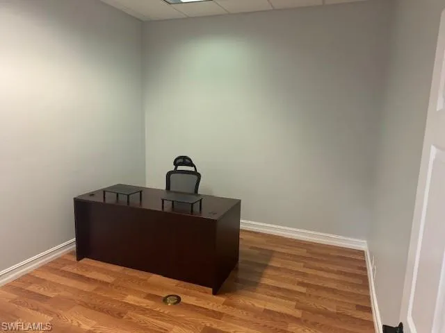Office area with hardwood / wood-style floors and a drop ceiling