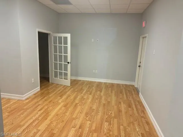 Unfurnished room featuring a drop ceiling and light hardwood / wood-style flooring