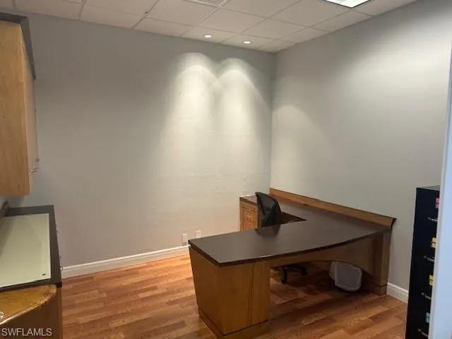 Office with a drop ceiling and hardwood / wood-style floors