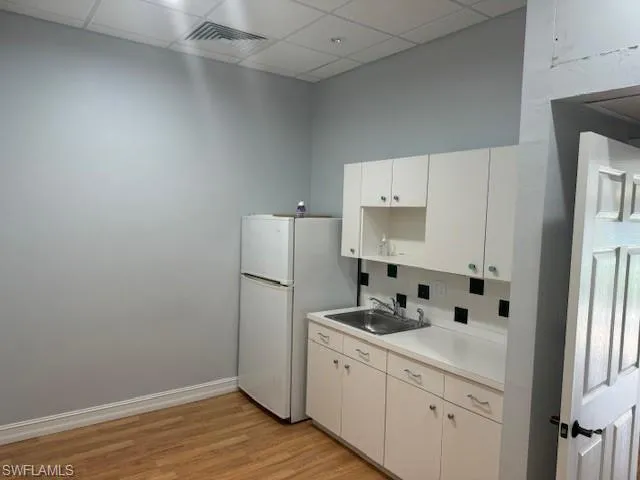Kitchen featuring a drop ceiling, sink, white cabinets, and white refrigerator