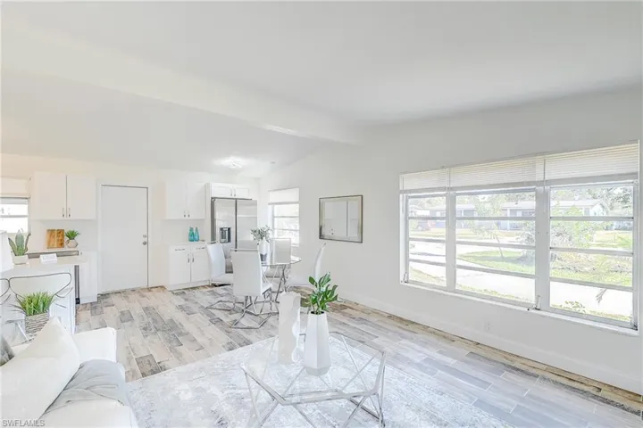 Living area with light wood-type flooring, baseboards, and lofted ceiling with beams