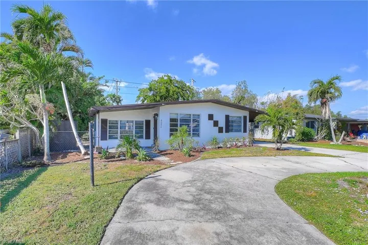 Single story home featuring a front yard, curved driveway, fence, and stucco siding