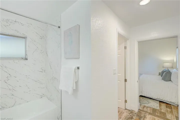 Bathroom featuring washtub / shower combination, connected bathroom, and wood finished floors