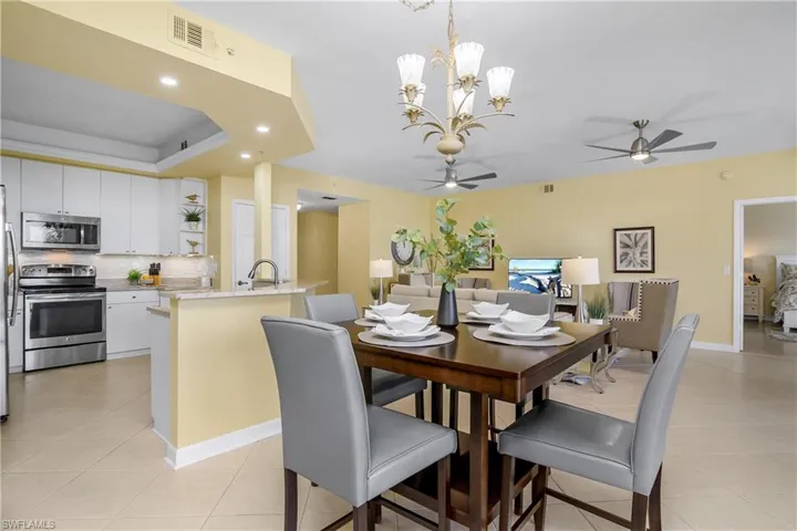 Tiled dining room with sink and ceiling fan with notable chandelier