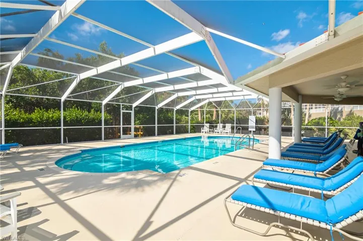 View of swimming pool with a patio area, glass enclosure, and ceiling fan