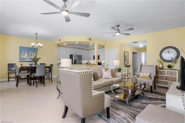 Tiled living room with ceiling fan with notable chandelier