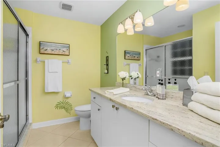 Bathroom with vanity, a shower with shower door, toilet, and tile patterned flooring