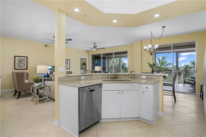 Kitchen with sink, white cabinetry, a wealth of natural light, stainless steel dishwasher, and light stone counters