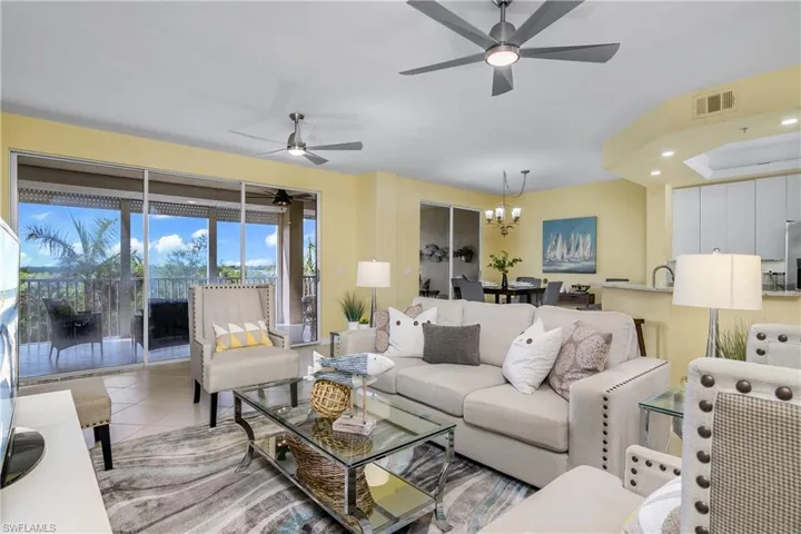 Tiled living room featuring sink and ceiling fan with notable chandelier