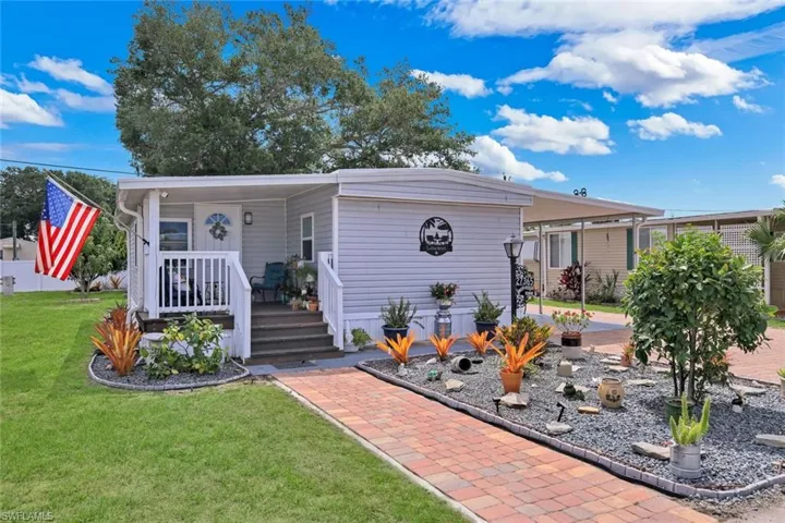 The property features a front porch with white railings and steps, leading to a front door