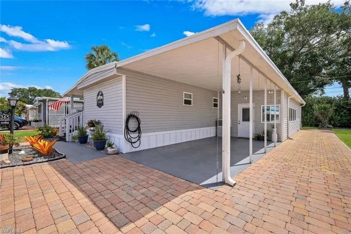 The property features a brick paver driveway and an attached carport with extra parking if needed or room for outdoor games or seating