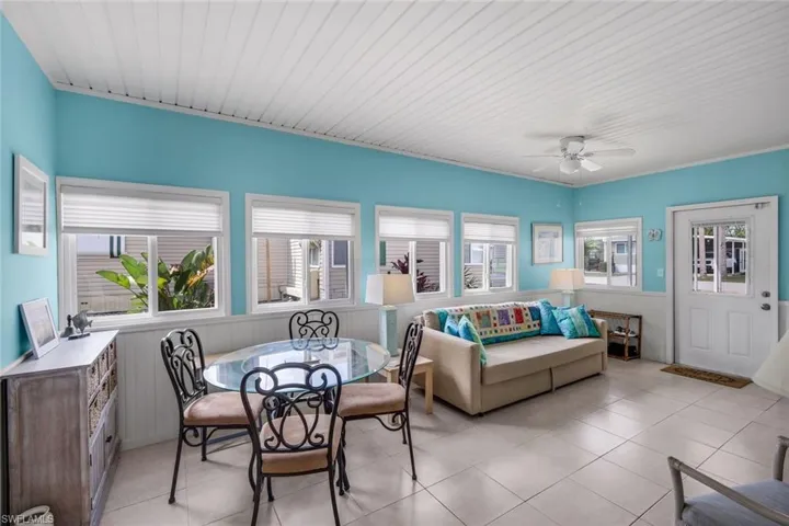 This bright living space features light blue walls, white wainscoting, and a white planked ceiling