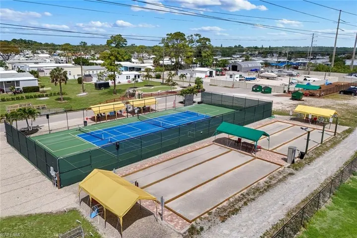The property features well-maintained pickleball courts with a surrounding fence, alongside dedicated bocce ball courts, all within a landscaped setting
