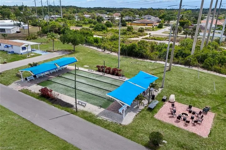 The property features bocce ball courts with blue shade structures, a paved fire pit area with seating, and a paved pathway