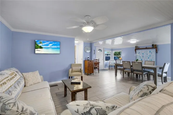 This property features an open-concept living and dining area with light blue walls, white trim, and light-colored tile flooring