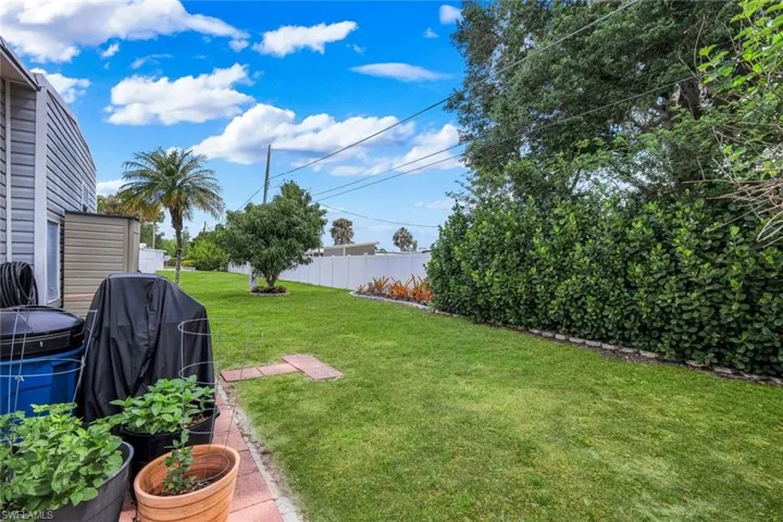 The property features a spacious lawn with mature trees and a neatly maintained hedge along the perimeter for privacy