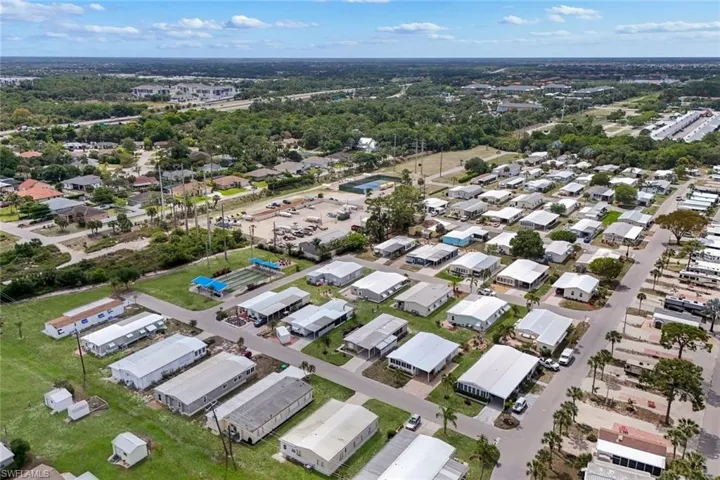 Aerial view showcasing the community layout with numerous residential units, paved roads, and green spaces