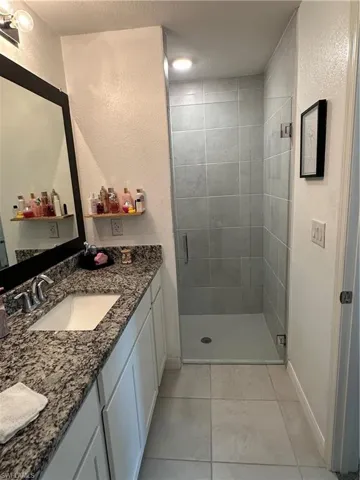 Bathroom featuring a single vanity with stone-finish countertop, undermount sink, and polished chrome faucet