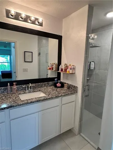 Bathroom featuring a white vanity with a granite-style countertop, undermount sink, and chrome faucet