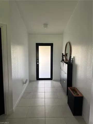 Entryway featuring light-toned tile flooring and white textured walls
