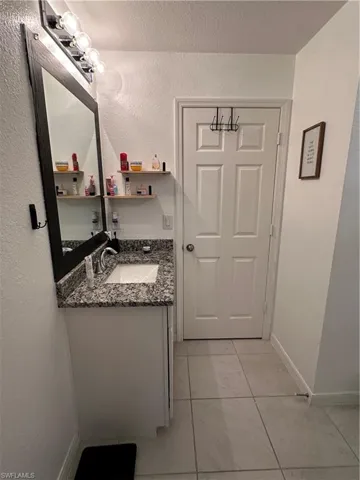 Bathroom vanity featuring a granite countertop, undermount sink, and chrome faucet