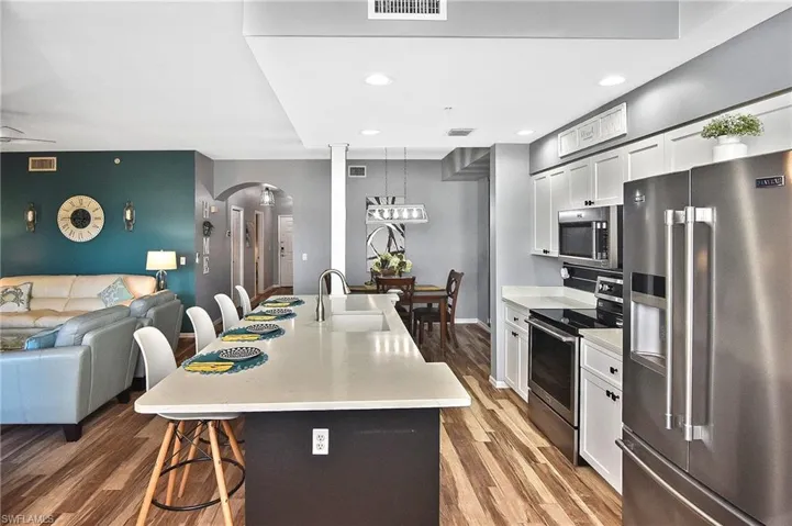 Kitchen with appliances with stainless steel finishes, arched walkways, a kitchen breakfast bar, open floor plan, and light countertops