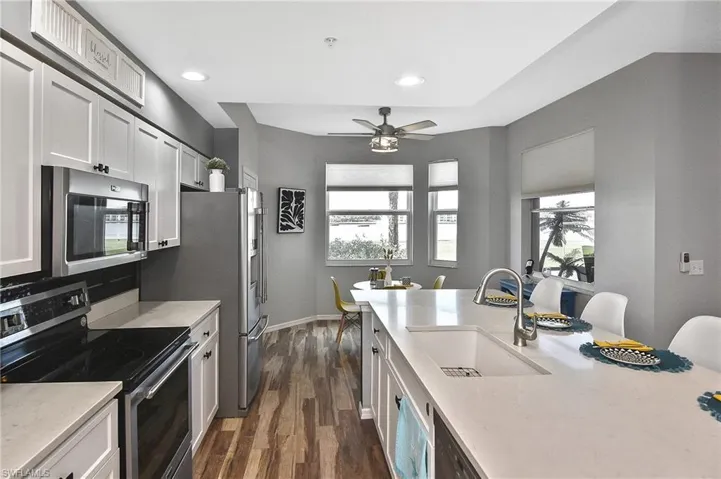 Kitchen featuring stainless steel appliances, dark wood-type flooring, recessed lighting, light stone counters, and white cabinets