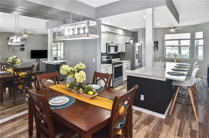 Kitchen featuring stainless steel appliances, a breakfast bar area, light countertops, wood finished floors, and backsplash