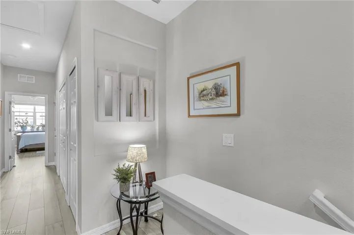 Hall featuring light wood-style floors, visible vents, and baseboards