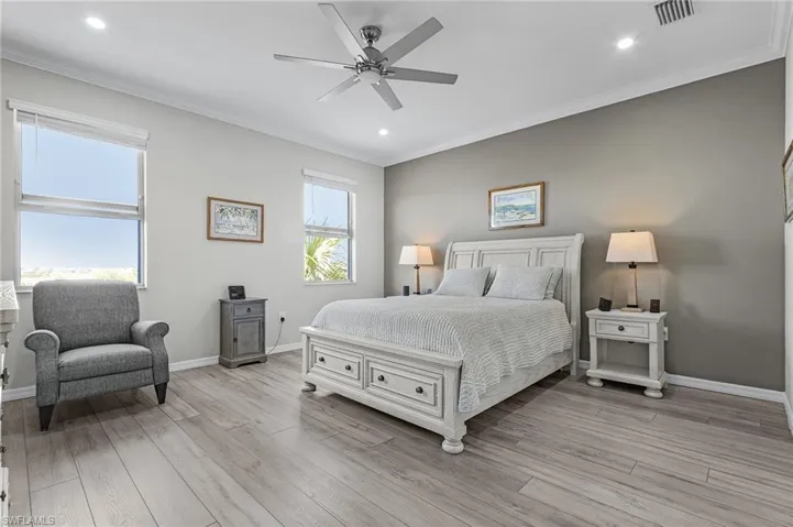 Bedroom featuring ornamental molding, light wood-style flooring, and visible vents
