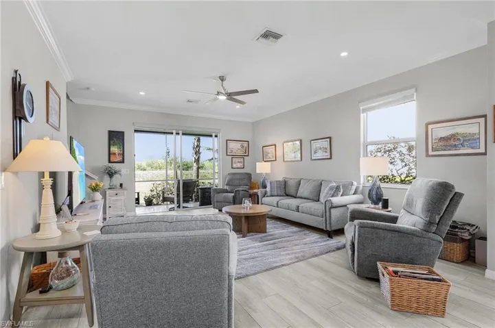 Living room with ornamental molding, recessed lighting, light wood-style flooring, and ceiling fan with notable chandelier