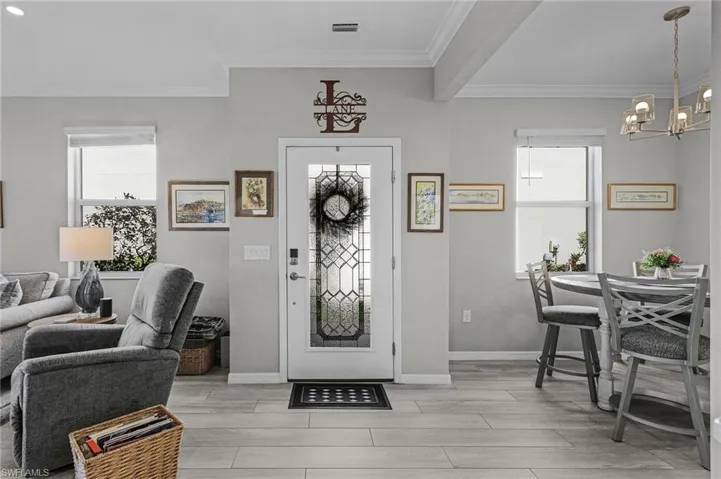 Entrance foyer featuring wood tiled floor, visible vents, crown molding, and baseboards