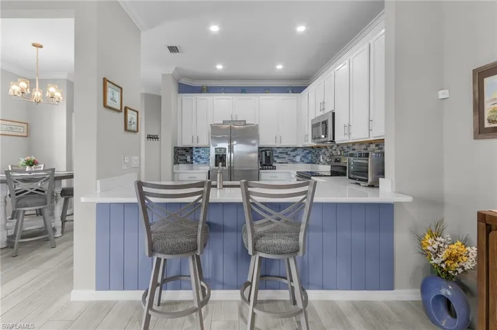 Kitchen with tasteful backsplash, visible vents, white cabinets, appliances with stainless steel finishes, and a peninsula