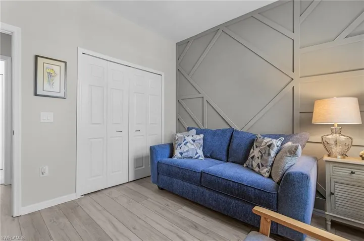 Living room with light wood-style flooring, baseboards, and a decorative wall