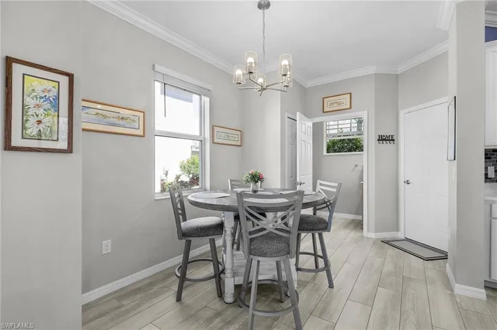 Dining area with a healthy amount of sunlight, baseboards, ornamental molding, and wood finish floors