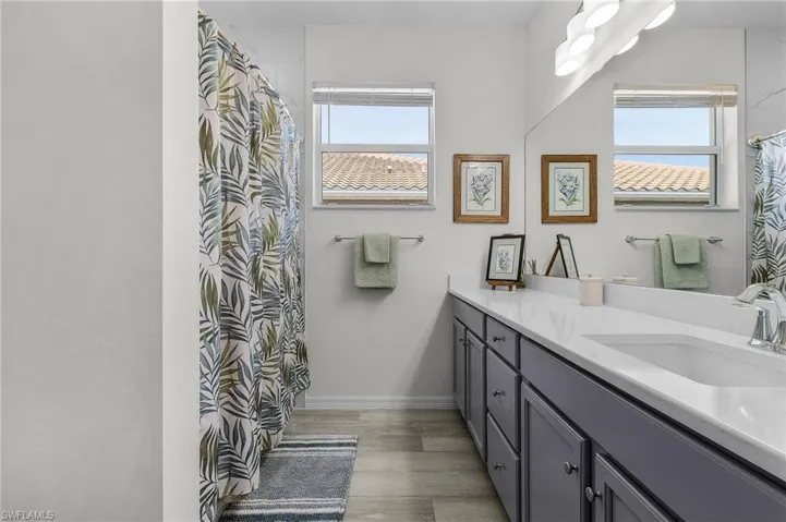 Bathroom featuring a shower with shower curtain, vanity, baseboards, and wood finished floors