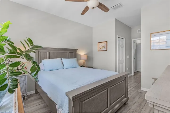 Bedroom with ceiling fan, light wood-style flooring, visible vents, and baseboards
