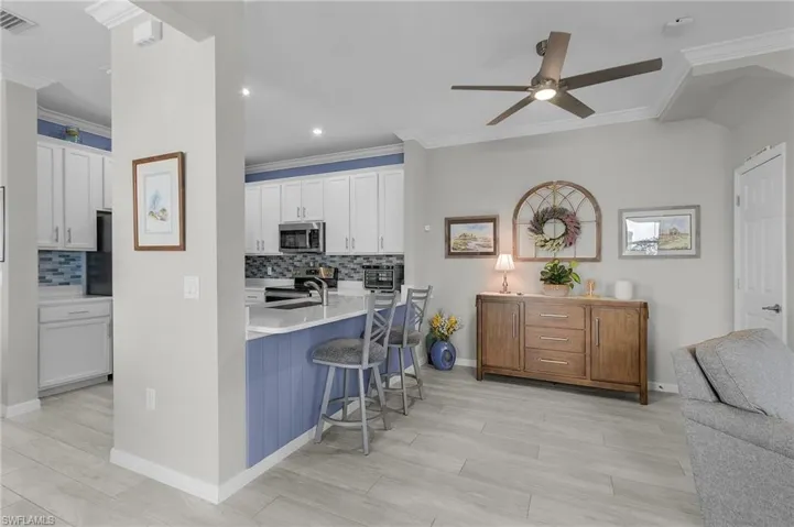 Kitchen featuring visible vents, white cabinets, a breakfast bar area, stainless steel appliances, and crown molding