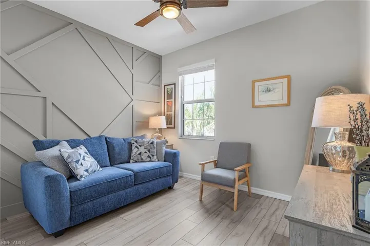 Living area featuring light wood-type flooring, ceiling fan, and baseboards