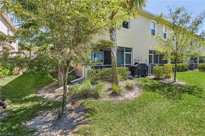 Rear view of property featuring cooling unit, a sunroom, and a lawn