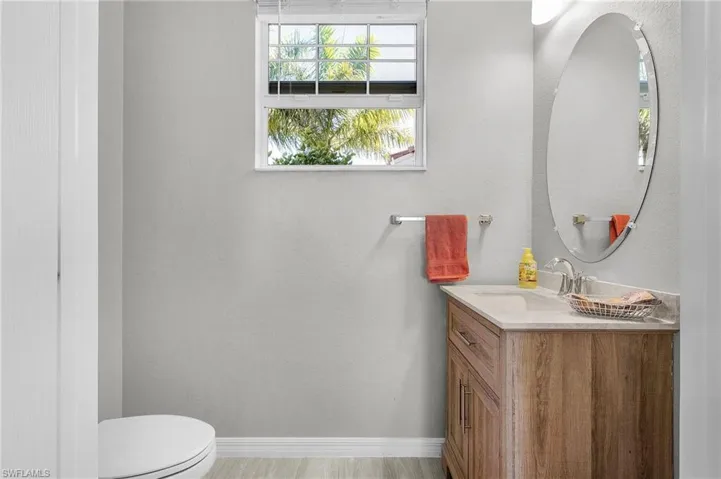 Half bath featuring toilet, baseboards, and vanity