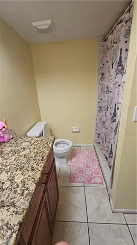Bathroom featuring toilet, vanity, tile patterned flooring, and a shower with curtain