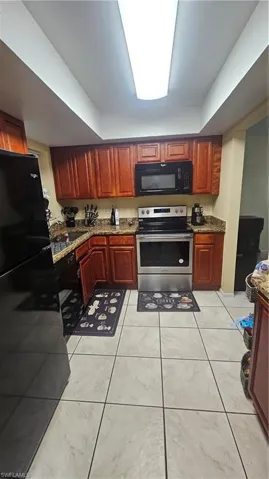 Kitchen with dishwashing machine, sink, fridge, dark stone counters, and stainless steel range