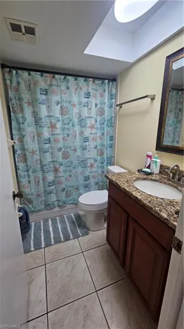 Full bathroom with toilet, tile patterned floors, shower / tub combo with curtain, and vanity