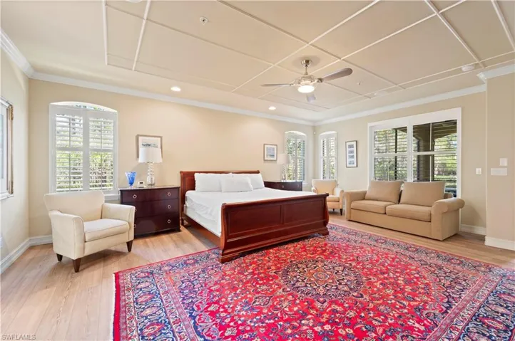 Bedroom featuring light wood-type flooring, a ceiling fan, multiple windows, and crown molding