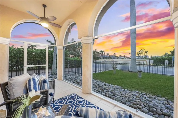 Screened in front lanai at dusk featuring the fenced front yard and ceiling fan.