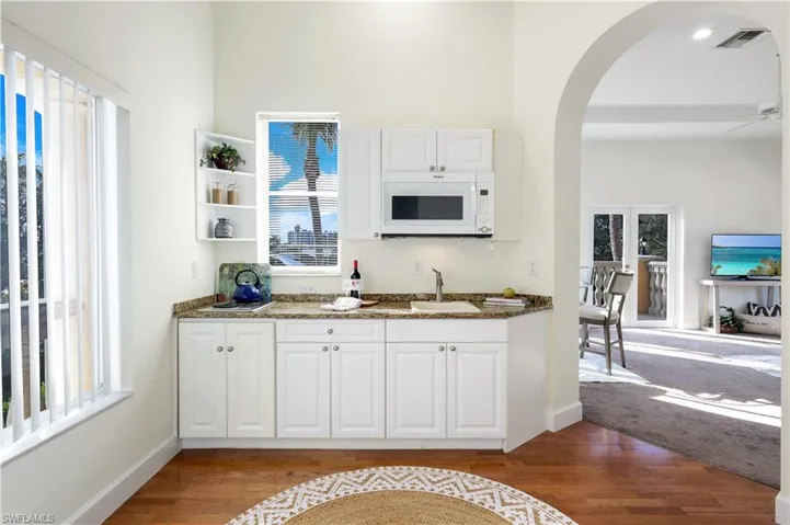 Second-floor kitchen featuring white cabinetry, a wealth of natural light, dark stone countertops, and light wood-type flooring.